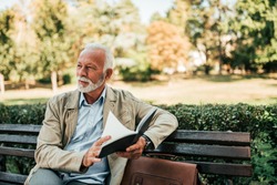 Handsome mature man reading book outdoors.