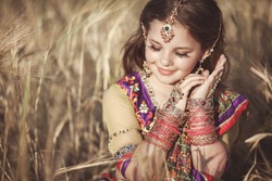 Happy little Indian girl outdoors in traditional sari. Cute little kid dancer enjoying countryside. beautiful baby girl on nature in wheat field. Girl bellydancer dancing