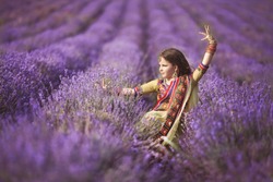 Beautiful little indian girl outdoors in lavender field, Aromatherapy. Adorable baby girl dancing at lavender flowers. Happy indian kid in traditional sari. Cute girl bellydancer.