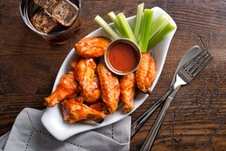 A serving of delicious spicy buffalo chicken wings on a pub style restaurant table top.