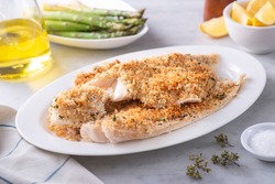 A plate of delicious panko breadcrumb crusted baked haddock with asparagus and lemon.