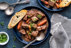 Delicious beef bourguignon stew with wine, carrots and onion garnished with parsley.