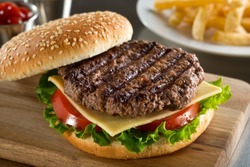 A delicious grilled Angus burger with cheese, lettuce, and tomato on a sesame seed bun.