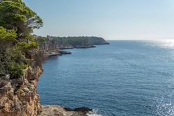 Aerial view of the rocky coast of the island of Mallorca on a sunny morning with the Mediterranean Sea with waves on the rocks. Nature background image