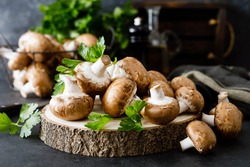 Raw mushrooms champignons on black background, cooking fresh champignons