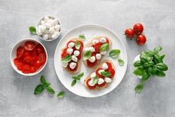 Caprese toasts with mini mozzarella cheese, cherry tomato and basil, top view