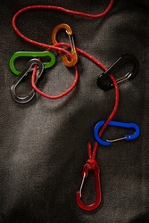 colourful carabiners accessories on a small red rope with dramatic low key lighting. This tool is not for climbing but usually for key chain or accessories
