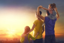happy family at sunset. father, mother and two children daughters having fun and playing in nature. the child sits on the shoulders of his father.