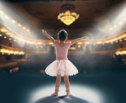 Cute little girl dreaming of becoming a ballerina. Child girl in a pink tutu dancing on the stage. Baby girl is studying ballet.
