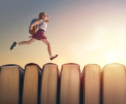 Back to school! Happy cute industrious child are running on books on background of sunset landscape. Concept of education and reading. The development of the imagination.                              