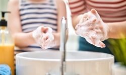 Kid and adult are washing their hands. Protection against infections and viruses. Close up.   