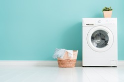 Interior of laundry room with a washing machine on bright teal wall background.