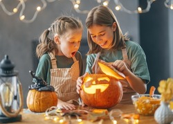 Cute little children girls with carving pumpkin. Happy family preparing for Halloween. 