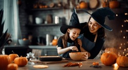 Mother and her daughter having fun at home. Happy Family preparing for Halloween. Mum and child cooking festive fare in the kitchen.
