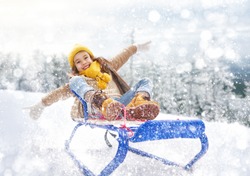 Child sledding. Little girl enjoying a sleigh ride. Child girl riding a sledge. Child plays outdoors in snow. Outdoor fun for family winter vacation.