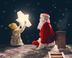 Merry Christmas and happy holidays! Cute little child girl and Santa Claus sitting on the roof and looking at Christmas star. Christmas legend concept.