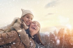 Happy loving family! Mother and child girl having fun, playing and laughing on snowy winter walk in nature. Frost winter season.