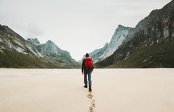 Man with red backpack walking alone at Horseid beach in Norway Travel lifestyle concept adventure outdoor summer vacations wild nature 