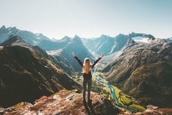 Woman traveler raised arms standing alone on cliff in mountains landscape Travel healthy Lifestyle adventure active vacations getaway in Norway 