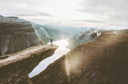 Man on Trolltunga cliff edge happy raised hands traveling in Norway adventure lifestyle extreme vacations outdoor sunset mountains landscape aerial view
