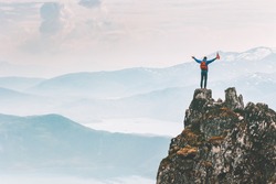 Man climber on mountain cliff summit traveling hike in Norway adventure vacations outdoor extreme activity healthy lifestyle traveler success raised hands Husfjellet peak 