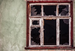 Smashed glass Window with old wooden frame on grunge wall damaged house