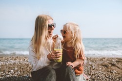 Family mother and daughter child drinking smoothie on beach healthy lifestyle vegan organic food travel vacations summer holidays outdoor happiness emotions cheerful people