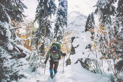 Traveler Man with backpack hiking in winter snowy forest landscape Travel Lifestyle concept adventure active vacations outdoor cold weather into the wild