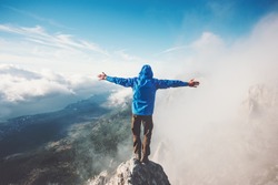 Happy Man on mountain summit enjoying aerial view hands raised over clouds Travel Lifestyle success concept adventure active vacations outdoor freedom emotions