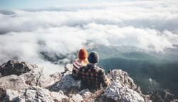 Couple Man and Woman sitting on cliff enjoying mountains and clouds landscape Love and Travel happy emotions Lifestyle concept. Young family traveling active adventure vacations