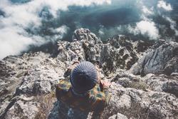 Man relaxing alone on rocky mountains cliff over clouds Travel Lifestyle emotions concept adventure active vacations outdoor top view