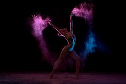 Slender girl dancing in color powder cloud