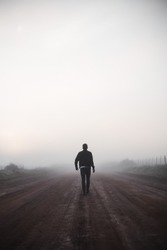Man walking alone on misty road