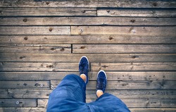A man walking on aged wooden floor, point of view perspective.