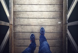 A man walking on aged wooden floor, point of view perspective.