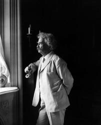 Mark Twain (Samuel L. Clemens, 1835-1910) American humorist standing by window in 1907 portrait.