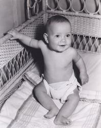Smiling baby boy sitting in crib