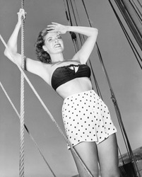 Young woman holding onto the ropes of an sail ship