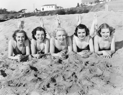 Portrait of five young women lying on the beach and smiling