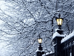 Antique street lamps on iron-wrought fence in the snow