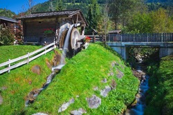 Wooden wheel of an ancient water mill in Dolomiti, water blurred by long exposition