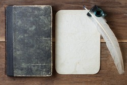 Book cover, quill and inkwell, old grunge paper on wood background