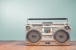Retro outdated portable stereo boombox radio receiver with cassette recorder from circa late 70s front mint green wall background. Listening music concept. Vintage old style filtered photo