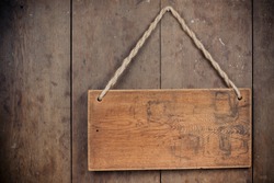 Wooden signboard with rope hanging on grunge planks background