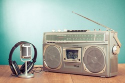 Retro radio and cassette player, headphones, microphone on table in front mint green background