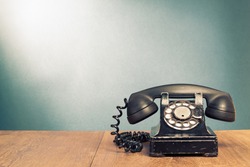 Retro black telephone on wooden table in front gradient background