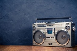 Retro boombox ghetto blaster outdated portable radio receiver with cassette recorder from 80s front concrete black wall background. Rap, Hip Hop music concept. Vintage old style filtered photo
