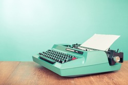 Retro old typewriter with paper on wooden table front mint green background