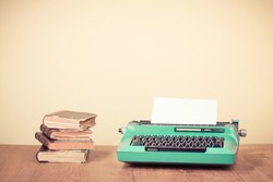Retro typewriter and old vintage books on wooden table near empty wall background