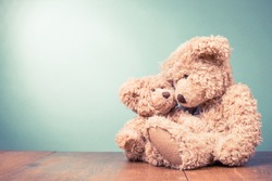 Two retro Teddy Bear toys family: parent with baby. Parenthood concept. Vintage old style filtered photo